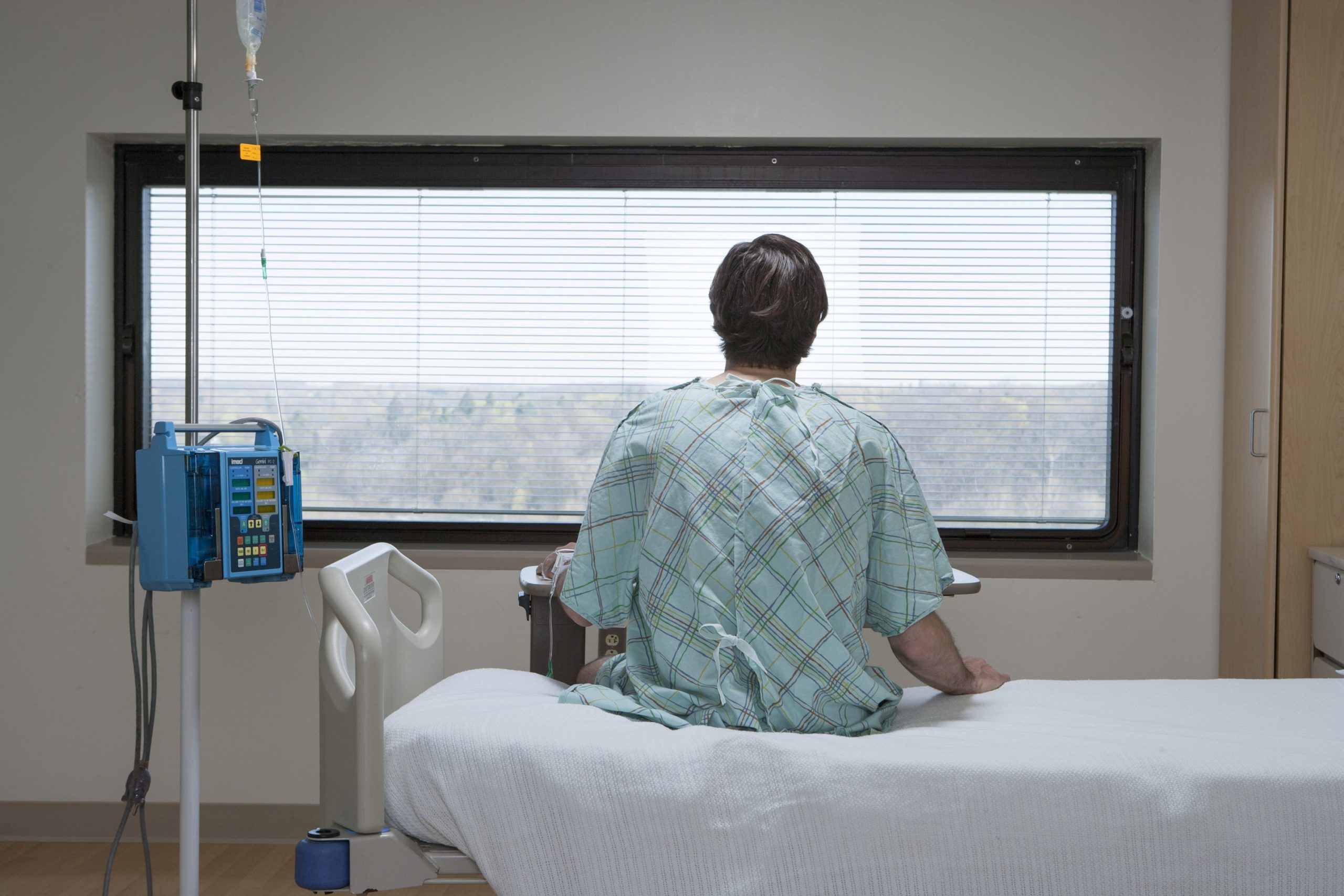Patient sitting at at hospital bed looking out window